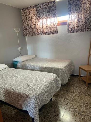 ロス・クリスティアーノスにあるCanary Islands Aptのベッド2台、テーブル、ランプが備わる客室です。