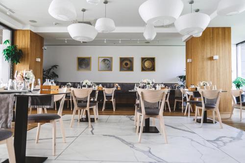 a dining room with tables and chairs and chandeliers at Poeme Mamaia Retreat in Mamaia