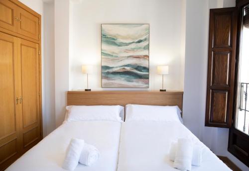 Apartamento Lomeña في غرناطة: غرفة نوم بسرير ابيض مع وسادتين