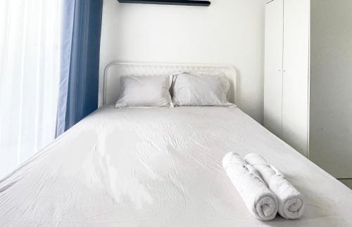 - un lit blanc avec des serviettes dans l'établissement Apartemen Sayana Harapan Indah by Cheapinn, à Tambun-lobangbuaja