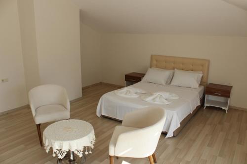 a bedroom with a bed and two chairs and a table at Tebriz Apart in Kemer