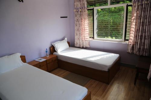 a small room with two beds and a window at Hotel Mount Paradise in Nagarkot