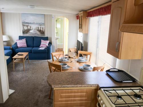 a kitchen and living room with a blue couch at Sea Breeze at Winthorpe Skegness in Skegness