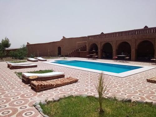 uma piscina com espreguiçadeiras e um pátio em Maison D’hôte Dar Panorama em Skoura