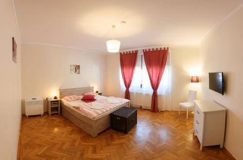 a bedroom with a bed and a window with red curtains at Meno Apartment in Sibiu