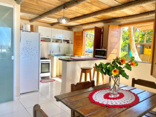 una cucina con tavolo in legno e vaso di fiori di Vila dos Gnomos Paraíso Místico Pé na Areia a Ilhéus