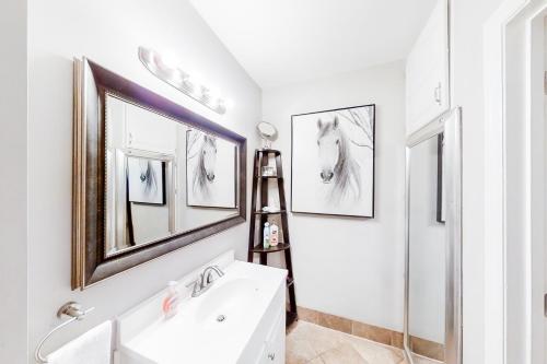 baño con lavabo blanco y 2 fotografías de caballos en la pared en Polk 401 en Nashville