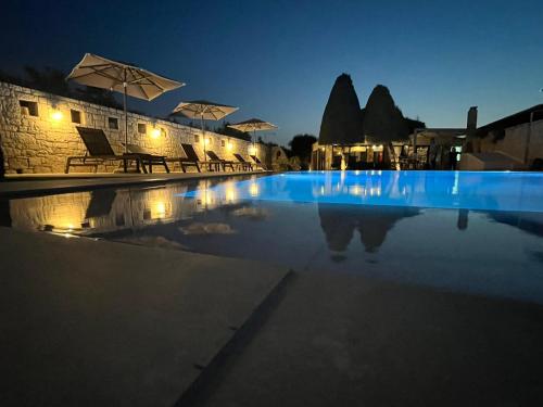a swimming pool at night with chairs and umbrellas at Nancy - Chara Apartments in Karteros