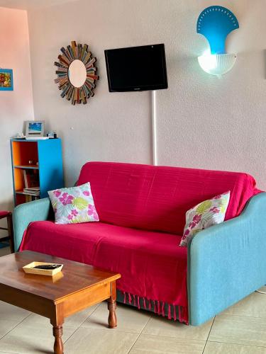 a living room with a red couch and a table at Les Hauts De Caritan in Sainte-Anne