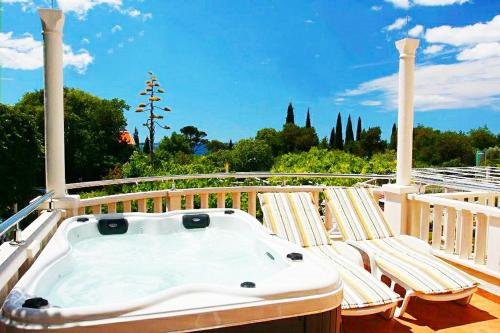 a hot tub on a deck with two lounge chairs at Apartments & Rooms Čakelić in Mlini