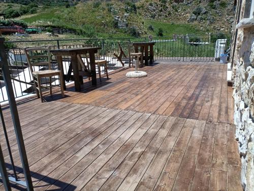 a wooden deck with tables and chairs on a balcony at Casolare La Torre in Scopello