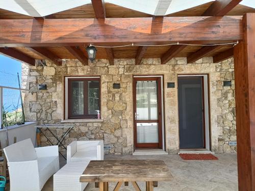 a patio with a stone wall and a wooden pergola at Casolare La Torre in Scopello
