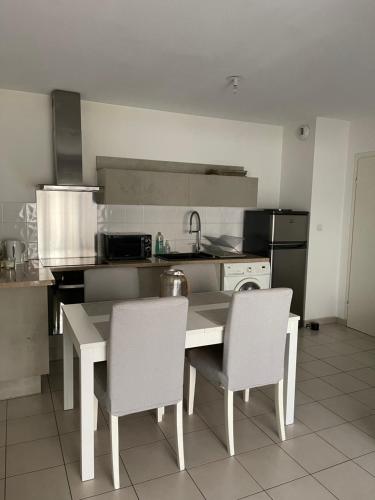 een keuken met een tafel en 2 stoelen. bij T2 Port Marianne avec balcon et place de parking in Montpellier