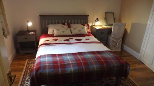 a bed with a plaid blanket and pillows on it at Small cosy bothy in Dingwall