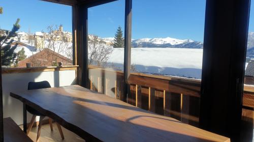 una mesa de madera en un balcón con vistas a las montañas cubiertas de nieve en Chalet 8 couchages à 100m du bas des pistes et commerces, en Les Angles