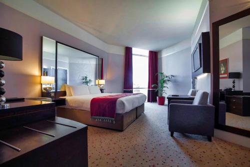 a large hotel room with a bed and a chair at Carlton Hotel Blanchardstown in Blanchardstown