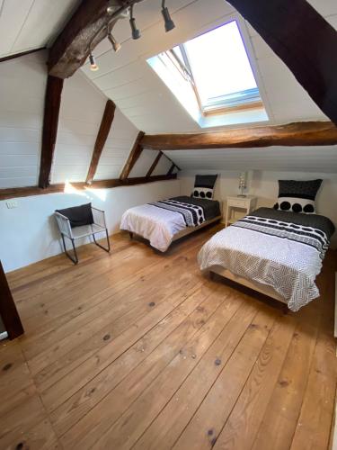 Cette chambre mansardée comprend 2 lits et une lucarne. dans l'établissement Maison en pierre à la campagne en Périgord Dordogne, à Saint-Germain-du-Salembre