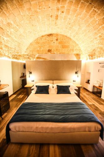 a bedroom with a large bed with a brick wall at Luna Federiciana Luxury Room & Spa in Altamura