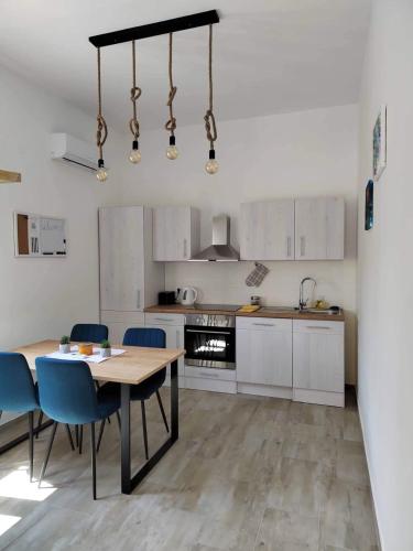 a kitchen with a wooden table and blue chairs at Apartment MAIO in Viskovo