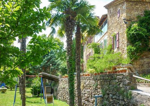 a building with palm trees next to a stone wall at Chambre d'hôte Mas d'Alzon à St Jean du Pin in La Barriére