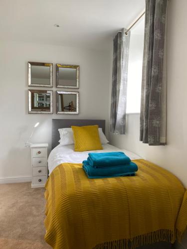 een slaapkamer met een bed met een gele deken bij The Mews - Family space, garden, parking, balcony, view in Adlington