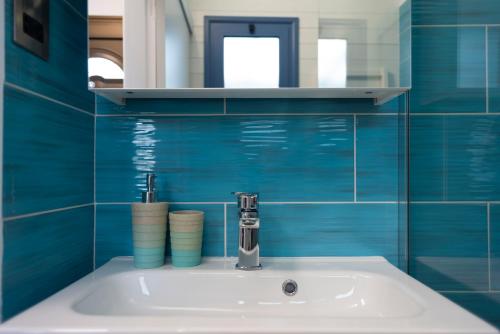 La salle de bains est pourvue de murs carrelés bleus et d'un lavabo. dans l'établissement Cyprusmylove, à Paphos