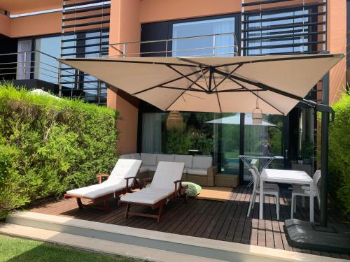 a patio with two chairs and an umbrella at Vill'Amar Tróia in Troia