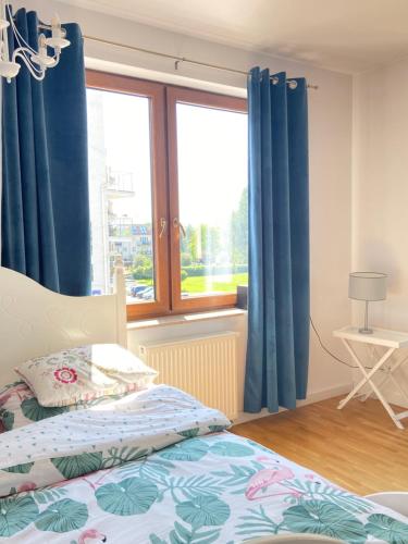 a bedroom with blue curtains and a bed and a window at Ełk Blue Apartment przy promenadzie in Ełk