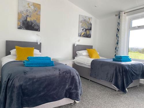 una camera con due letti con lenzuola blu e una finestra di South Cottage - Garden, Views, Parking, Dogs, Cheshire, Walks, Family a Adlington