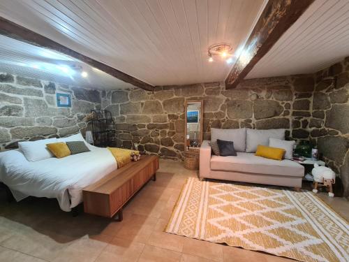sypialnia z łóżkiem i kanapą w kamiennej ścianie w obiekcie A aira da xoaniña w mieście Allariz