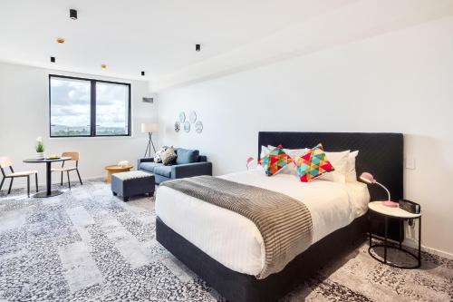 a bedroom with a bed and a living room at Roomie Apartment Hotel in Auckland