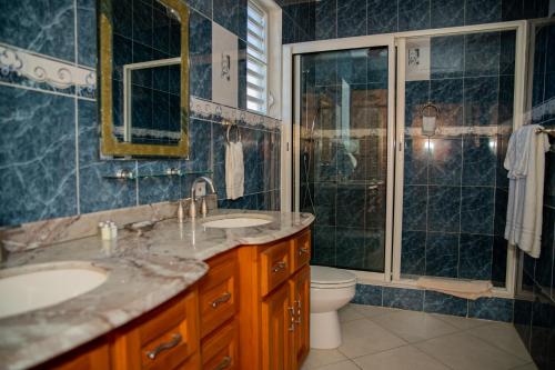 a bathroom with two sinks and a shower and a toilet at Easy Corner Villas in Sandy Ground Village