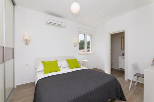 蘇提萬的住宿－Apartment Reful，白色卧室配有一张带绿色枕头的大床