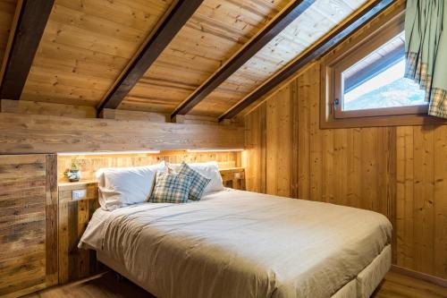 a bed in a room with wooden walls and a window at Chambres d'hôtes La Moraine Enchantée in Aosta