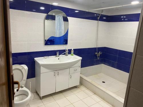 Friend's House rooms near Airport في يريفان: حمام ازرق وابيض مع مغسلة ومرحاض