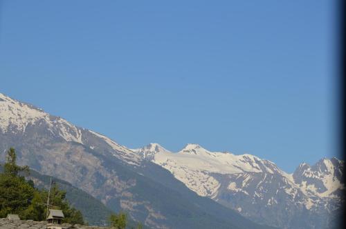 a snow covered mountain with a house in front of it at Chambres d'hôtes La Moraine Enchantée in Aosta