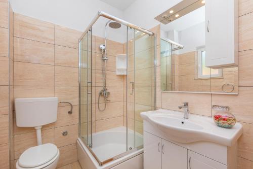 e bagno con doccia, servizi igienici e lavandino. di Olive tree apartment 1 a Prijevor