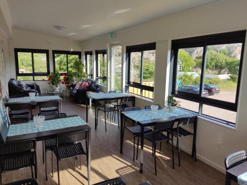 ein Restaurant mit Tischen, Stühlen und Fenstern in der Unterkunft Kungshamns Vandrarhem in Kungshamn