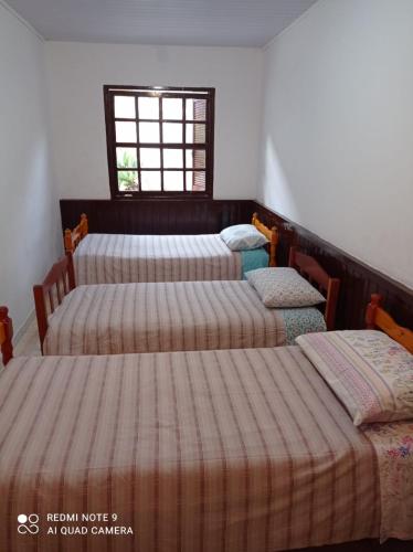 a group of four beds in a room with a window at Casa Recanto 2 in Campos do Jordão