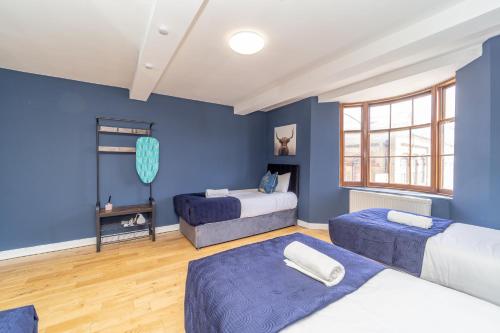 a bedroom with two beds and a blue wall at NEXT TO BRIGHTON STATION THREE BEDROOM FLAT SLEEP 10 Guests in Brighton & Hove