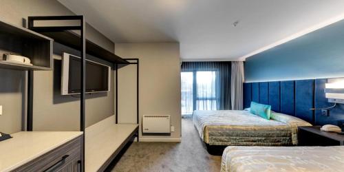 une chambre d'hôtel avec deux lits et une cuisine dans l'établissement Distinction Luxmore Hotel, à Te Anau