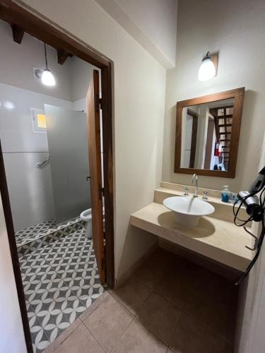 y baño con lavabo, espejo y aseo. en Cabañas La Escondida en San Lorenzo