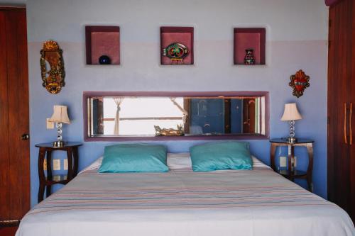 a bedroom with a bed with a window and some pictures at Tres Mujeres Hotel in Troncones