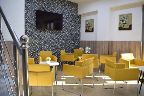 a waiting room with yellow chairs and a flat screen tv at Hôtel Zinou zm in Alger