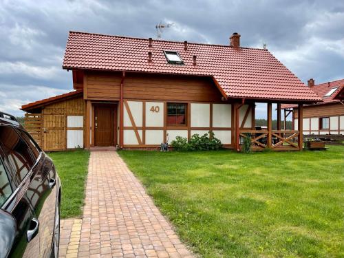 a house with a red roof and a green yard at Kaszubska Odskocznia Ostoja Bukowo in Borowy Młyn