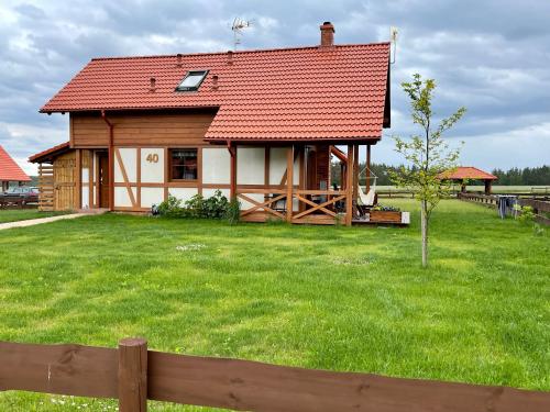 a house with a red roof on a green field at Kaszubska Odskocznia Ostoja Bukowo in Borowy Młyn