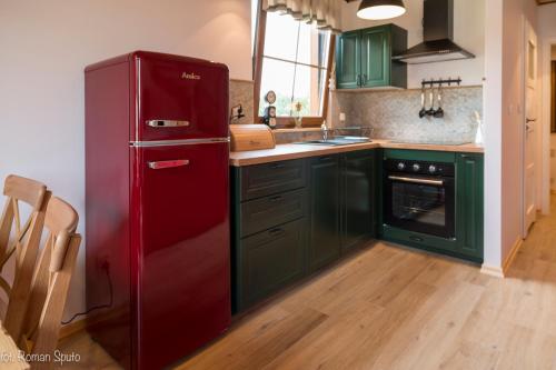 a red refrigerator in a kitchen with green cabinets at Kaszubska Odskocznia Ostoja Bukowo in Borowy Młyn