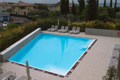 a large swimming pool with chairs on a patio at Hotel Relais Agli Olivi in Lazise