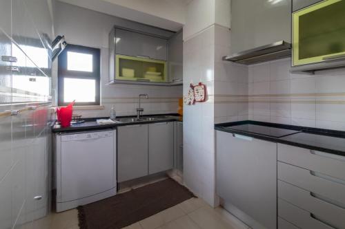 uma cozinha com armários brancos, um lavatório e uma janela em THE PENTHOUSE IN AMARILIS em Portimão