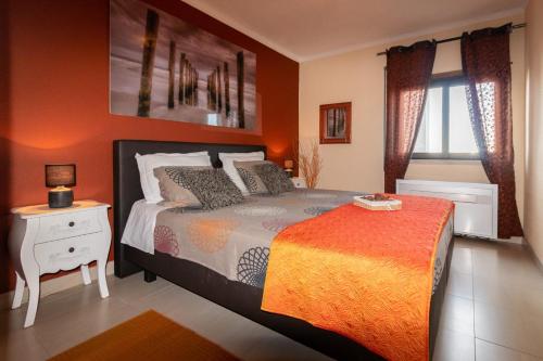 a bedroom with a bed with an orange wall at THE PENTHOUSE IN AMARILIS in Portimão
